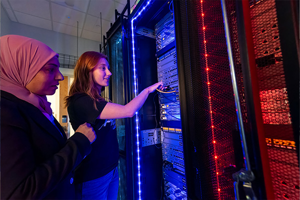 Cybersecurity student in a glowing server room with a professor.