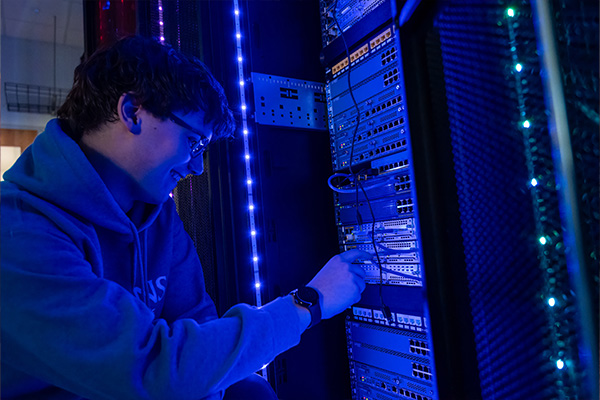 Cybersecurity student working on illuminated servers.