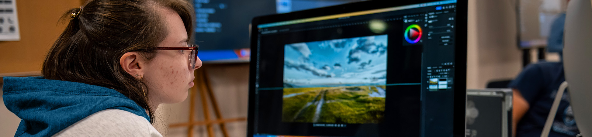 Computer graphics student working at a mac adjusting visuals on the screen.