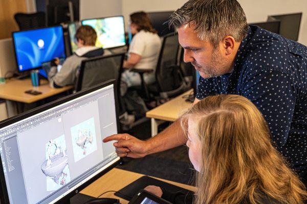 professor helping animation student on computer