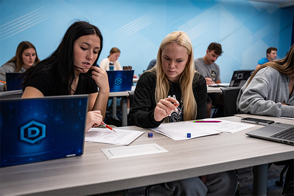 DSU students sit at a desk examining rolled dice