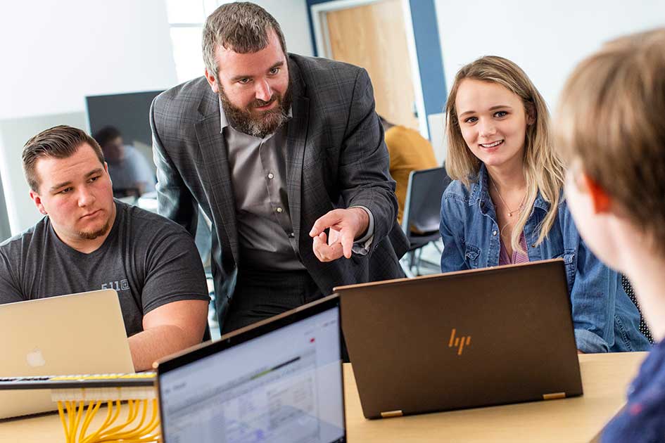 students working on laptop with instructor