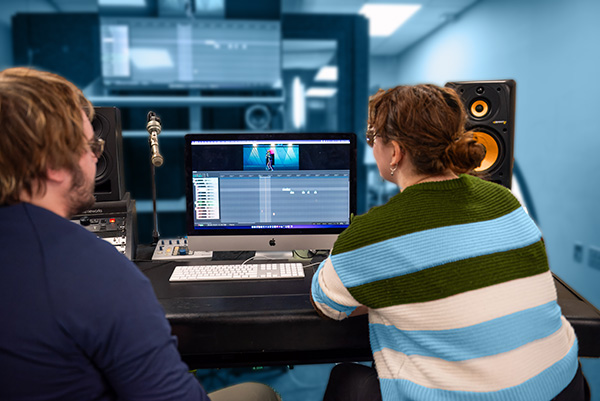 Two students working on computer in sound studio.