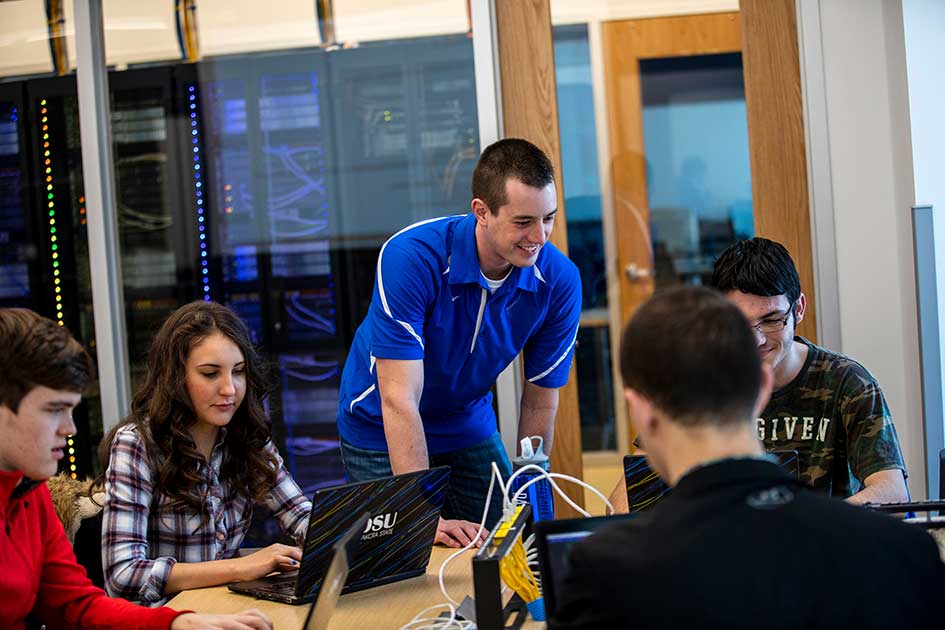 Faculty engaging with multiple students in the classroom.