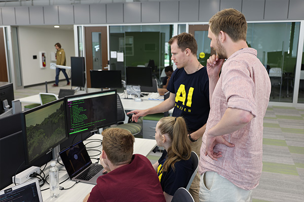 masters students looking at code on a computer