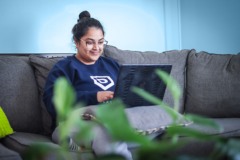 Student working on computer on a couch.