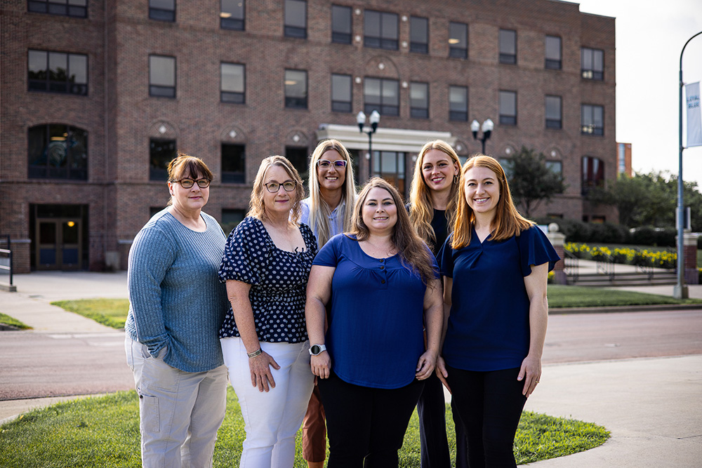 DSU Registrar Team standing outside of Heston hall with Amy Prigge, Nancy Gacke, Des Branco, Laura Cross, Katharine Comes, and Autumn Glanzer