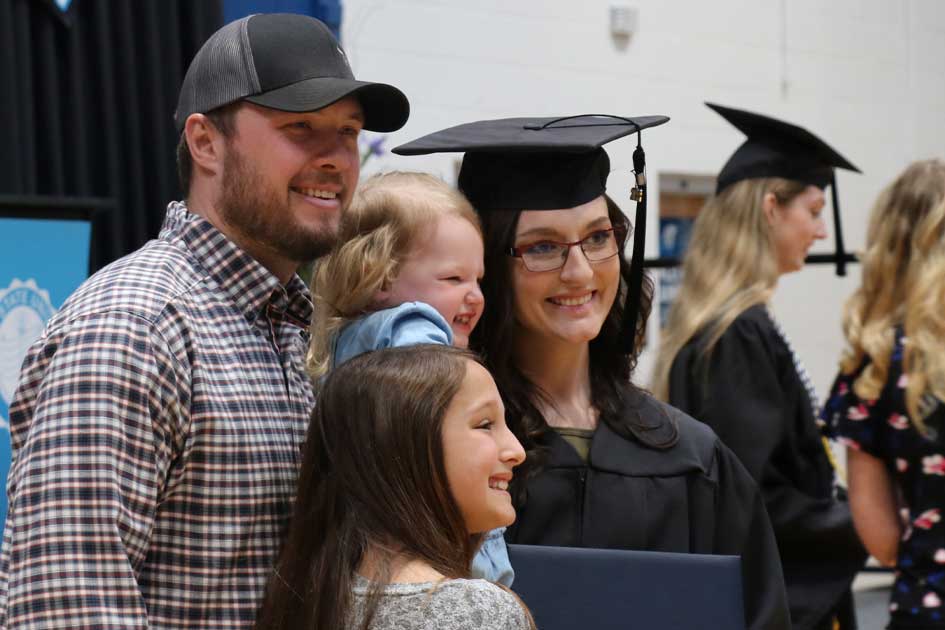 Dakota State University graduate with her family celebrating by capturing the event on camera.