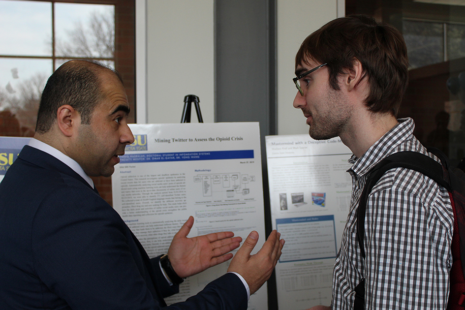 Faculty and student displaying research poster boards