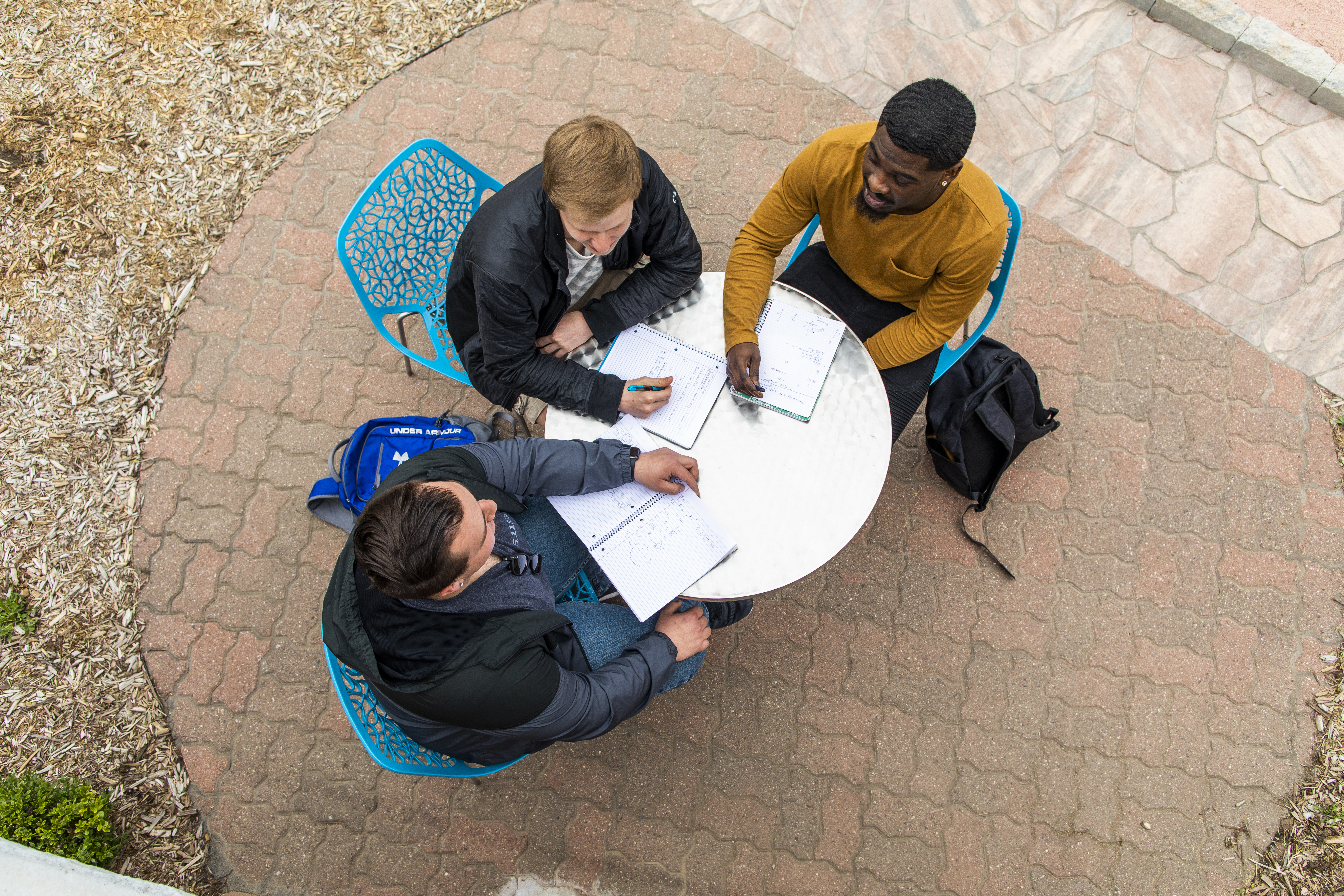 Arial photo of students sitting at a round table in an outdoor courtyard studying