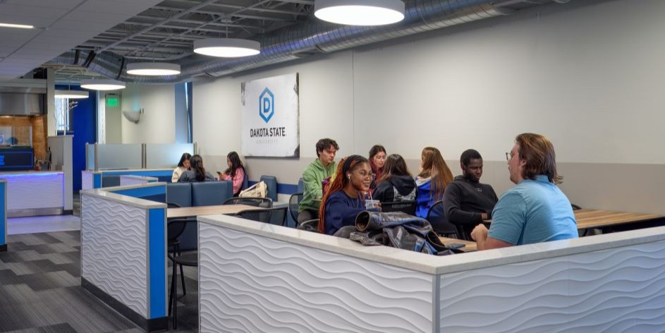 Students sitting at table in the Trojan Center at the queue