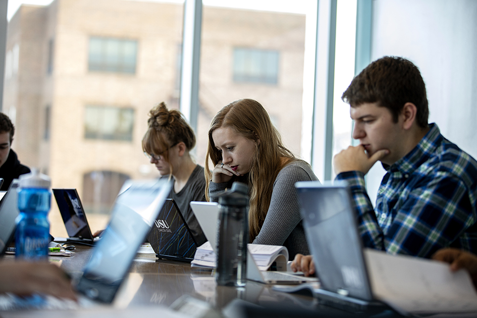 students at table looking at laptops