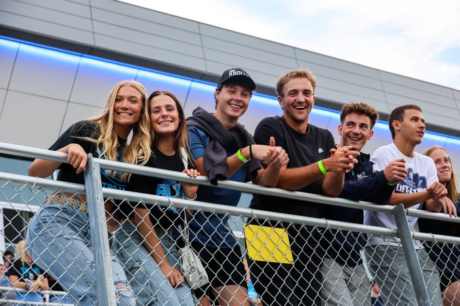 dsu students at football game leaning on fence