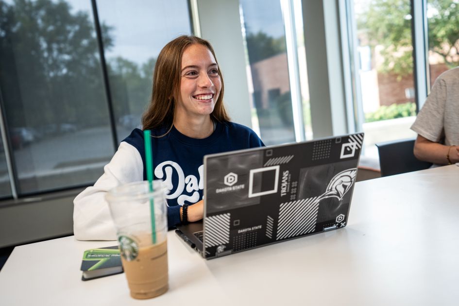 online student working on computer smiling