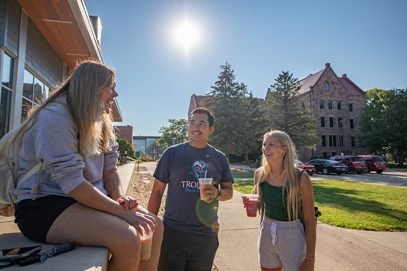 students chatting on campus while holding coffee