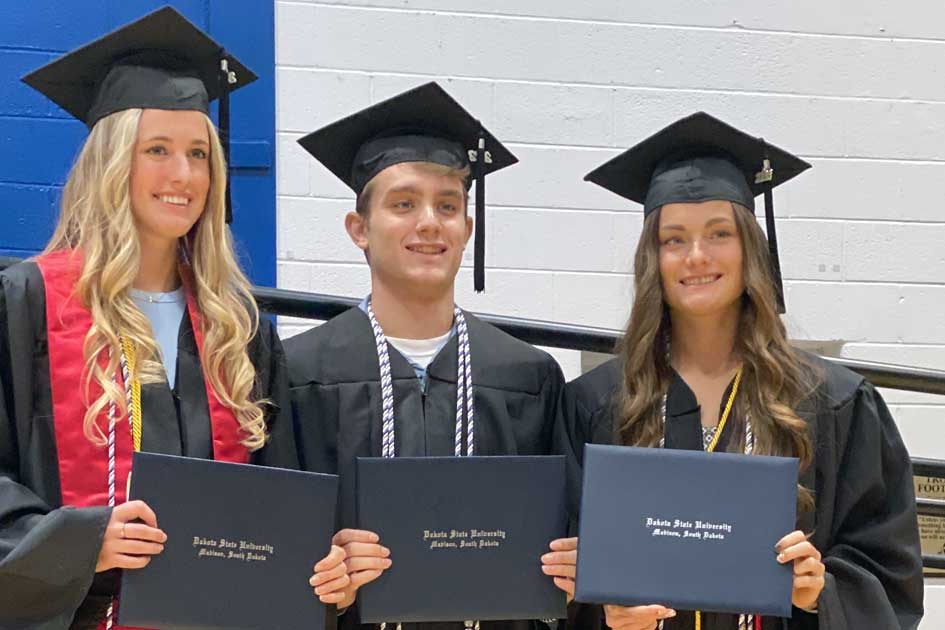 Three DSU grads holding up their diplomas